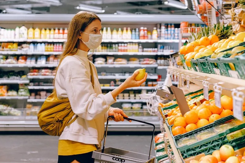 A shopper choosing fruit at a neighborhood grocery store